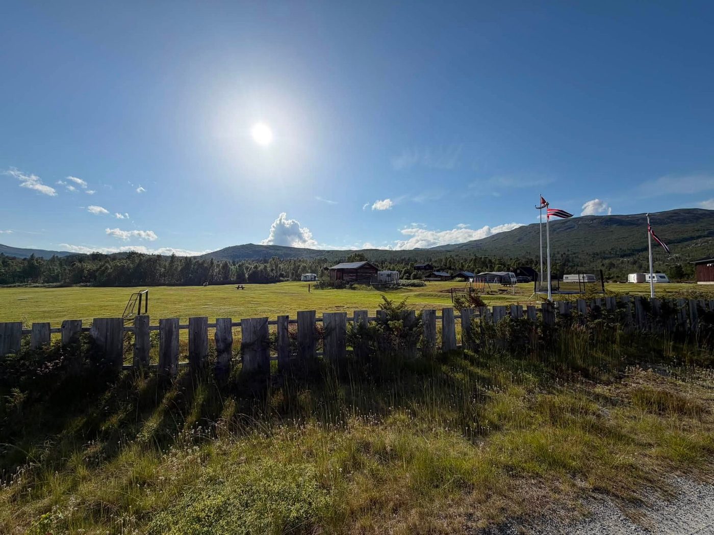 Open field with playground equipment and mountain view at Stuttgången Camping
